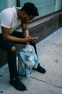 home assegut, costat, celebració, telèfon, home, seient, al costat, telèfon mòbil, homes, gent, missatge de text, una persona, assegut, telèfon intel·ligent, ètnia africana, a l'aire lliure, mascles, adult jove, adult, descendència africana, roba casual, estils de vida, escena urbana, tecnologia, vida de ciutat, un sol home, tecnologia sense fils, persones reals, longitud completa, comunicació, home jove, activitat d'oci, utilitzant el telèfon, dispositiu d’informació portàtil, adolescència, nois adolescents, adolescent, 5K