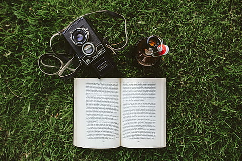 grass, Book, reading, leaf, literature, outdoors, camera - Photographic Equipment, summer, music, high angle view, communication, directly above, arts culture and entertainment, plant, green color, day, nature, publication, land, field, no people, growth, technology, paper, open, headphones, 4K, CC0, public domain, royalty free