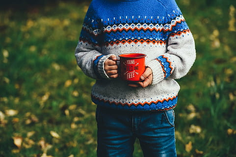 cup, grass, hands, kid, knitwear, macro, mug, sweater, one person, focus on foreground, clothing, casual clothing, day, standing, holding, midsection, field, land, real people, warm clothing, front view, plant, nature, adult, food and drink, women, outdoors, jeans, 4K, CC0, public domain, royalty free