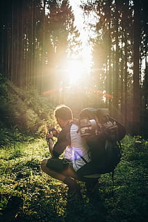 man, tar, sitta på huk, Foto, gräs, gyllene, timme, ryggsäck, Sammanträde, innehav, kamera, skog, backpacking, träd, Sol, person, vandrare, fotograf, ryggsäcks, utomhus-, vandring, camping, reslust, äventyr, natur, resa, utforska, Upptäck, växt, landa, solljus, riktiga människor, fritidsaktivitet, livsstilar, två personer, samhörighet, tillväxt, linsflare, kvinnor, människor, dag, solstråle, honor, vardaglig klädsel, full längd, fält, utomhus, positiva känslor, par - relation, ljus, 2K, CC0, offentligt domän, royaltyfria