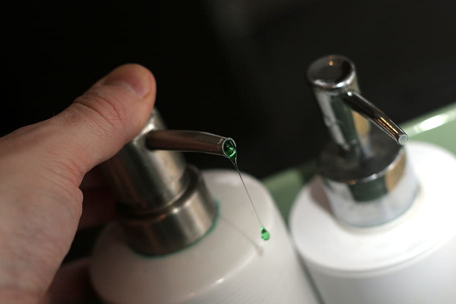 Person, halten, Flasche, Pumpe, Seife, Flüssigkeit, tropfen, Waschmittel, Gel, Lotion, menschliche Hand, Hand, menschliches Körperteil, drinnen, Nahansicht, Studioaufnahme, Finger, schwarzer Hintergrund, menschlicher Finger, Vorbereitung, Menschen, High Angle View, Haushaltsausstattung, zwei Objekte, Essen und Trinken, gesunder Lebensstil, Einfachheit, Fokus auf den Vordergrund, 2K