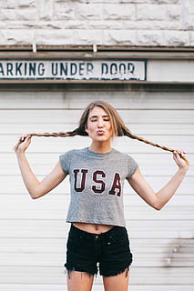 woman, gray, crew-neck crop, top, black, denim, short, shorts, standing, behind, white, door, daytime, crew-neck, crop top, short shorts, women, one Person, caucasian Ethnicity, outdoors, people, females, young Adult, human body part, human arm, limb, arms raised, text, real people, lifestyles, front view, young women, casual clothing, portrait, three quarter length, hairstyle, communication, long hair, looking at camera, leisure activity, western script, architecture, hair, beautiful woman, teenager, 4K, CC0, public domain, royalty free