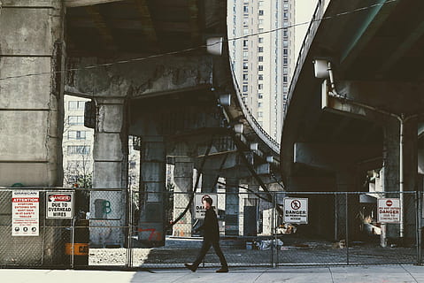 man, walking, sidewalk, architecture, building, infrastructure, sky, skyscraper, tower, city, urban, fence, caution, sign, construction, people, alone, urban Scene, built structure, one person, full length, real people, transportation, text, standing, building exterior, communication, day, lifestyles, casual clothing, connection, men, adult, young adult, 2K, CC0, public domain, royalty free