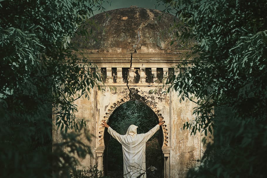 persona, blanco, abrigo con capucha, arco, vistiendo, capa, árbol, edificio, estructura, estructura construida, arquitectura, religión, creencia, una persona, gente real, planta, espiritualidad, vista trasera, día, lugar de adoración, estilos de vida, actividad de ocio, turismo, historia, al aire libre, brazo humano, 5K
