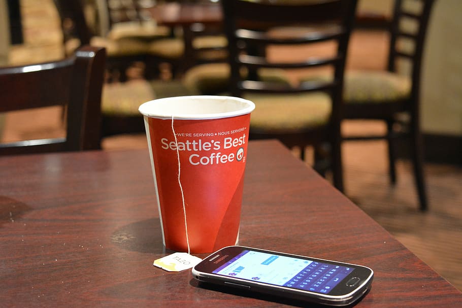 Telefon, Entspannen Sie Sich, Tabelle, Tee, Cafe, sozialen Medien, chatten, Kaffee trinken, Getränk, Essen und Trinken, Erfrischung, Kommunikation, Tasse, drinnen, kabellose Technologie, Technologie, Mobiltelefon, Smartphone, Fokus auf den Vordergrund, tragbares Informationsgerät, Kaffee, Becher, Trinkglas, Text, Restaurant, Glas, Bartheke, Café, Geschirr, 5K