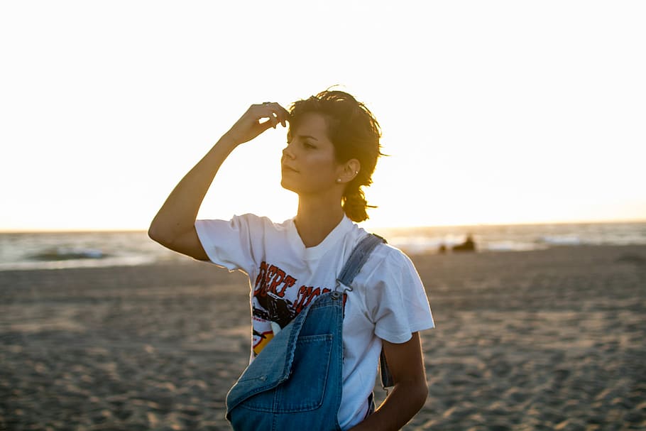 dona, de peu, vora del mar, celebració, cap, dona que sosté el front, retrat, pensar, model, sorra, aigua, platja, cabell, denim, dungarees, samarreta, mà, posta de sol, arracades, bonic, diversió, una persona, terra, cel, adult jove, mar, naturalesa, activitat d'oci, roba casual, adult, cintura cap amunt, dones, estils de vida, vacances, pentinat, a l'aire lliure, braços aixecats, braç humà, 1080P