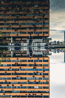 home, de peu, frontal, marró, concret, de gran alçada, edifici, durant el dia, reflectint, aigua, reflexionar, reflexió, gratacels, apartament, bloc de pisos, escena urbana, arquitectura, exterior de l'edifici, estructura construïda, ciutat, paisatge urbà, edifici d'oficines, industria de la construcció, districte del centre de la ciutat, vida de ciutat, a l'aire lliure, horitzó urbà, longitud completa, dia, transport, persones reals, cel, manera de transport, una persona, naturalesa, vehicle terrestre, núvol - cel, estils de vida, homes, 5K, CC0, domini públic, lliure de regalies