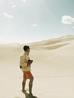 bruin overhemd, man, bruin, knop, jas, staand, zand, dag, vent, duinen, woestijn, shorts, camera, fotograaf, zonneschijn, blauw, hemel, een man alleen, een persoon, alleen mannen, alleen volwassenen, bezit, volledige lengte, Draadloze technologie, communicatie, volwassen, echte mensen, vrijetijdsbesteding, levensstijlen, land-, scenics - natuur, niet-stedelijke scène, natuur, schoonheid in de natuur, casual kleding, wolk - lucht, technologie, jonge mannen, jonge volwassene, kalmte, buitenshuis, 2K, CC0, publiek domein, royaltyvrij