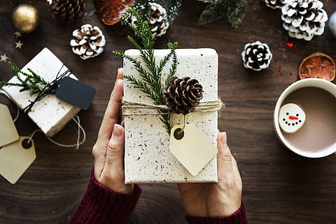 rechthoekige witte doos, doos, kaart, vieren, viering, Kerstmis, versieren, decoratie, festival, feestelijk, gift, hangen, vakantie, label, Nieuwjaar, gelegenheid, dennenappels, aanwezig, seizoen, traditie, winter, verpakt, yule, kersttijd, tafel, bezit, hoge hoekmening, een persoon, menselijke hand, menselijk lichaamsdeel, binnenshuis, hand-, eten en drinken, fabriek, volwassen, recht boven, papier, levensstijlen, drinken, kop, hout - materiaal, natuur, 5K, CC0, publiek domein, royaltyvrij