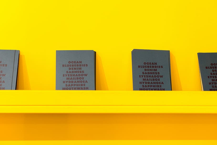 blau i groc, quatre, assortit, llibres, inclinat, groc, pintat, paret, prestatge, llibre, signe, cap gent, tir de l'estudi, a l'interior, arquitectura, fons de colors, negocis, text, color vibrant, Finances, ciutat, primer pla, senzillesa, comunicació, fons groc, modern, funció de construcció de parets, còpia espai, multicolor, 5K
