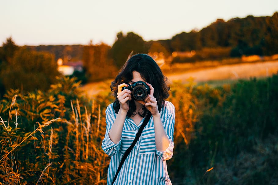 selektiv, fokus fotografering, kvinde, iført, krikand, hvid, stribet, albue-sleeved bluse, kvinde tager billeder, tager billeder, natur, udendørs, kikkert, mennesker, kamera - fotografisk udstyr, en person, leder, fotograf, kaukasisk etnicitet, smilende, hobbyer, Kvinder, fotografering temaer, fotografere, digitalt kamera, voksen, teknologi, bedrift, aktivitet, beskæftigelse, stående, afslappet tøj, fotografisk udstyr, ung voksen, fritidsaktivitet, forfra, fokus på forgrunden, portræt, livsstil, frisure, 5K