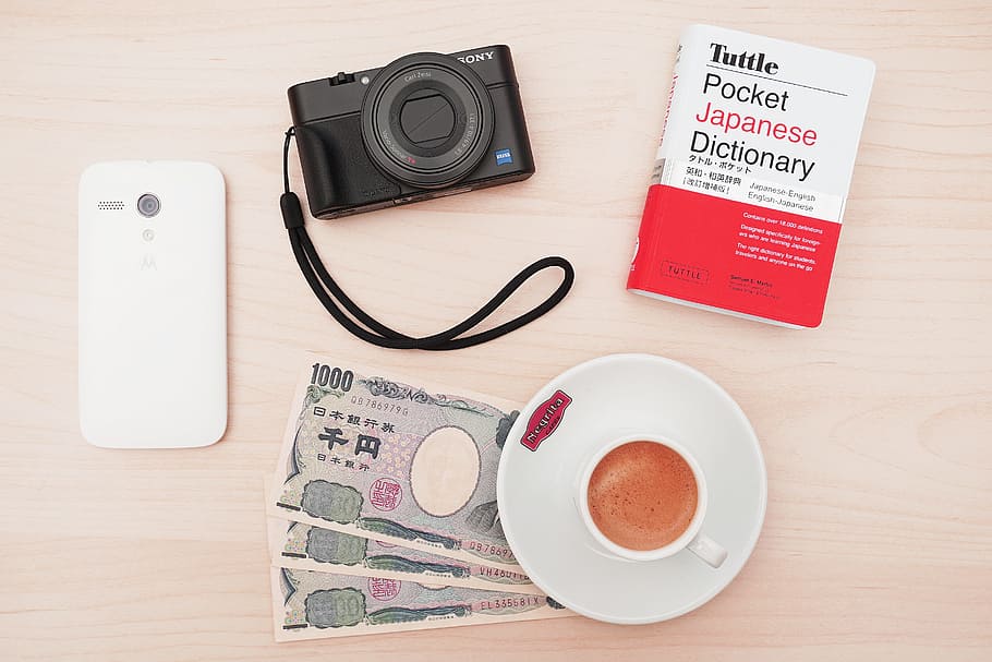 càmera, sony, mòbil, tecnologia, llibre, diners, diccionari, ien, placa, te, tassa, taula, cafè, menjar i beguda, natura morta, directament a sobre, tassa de cafè, cafè - beguda, beure, a l'interior, comunicació, Finances, cap gent, text, refresc, material de fusta, gots, vista d’angle alt, vaixella, 5K