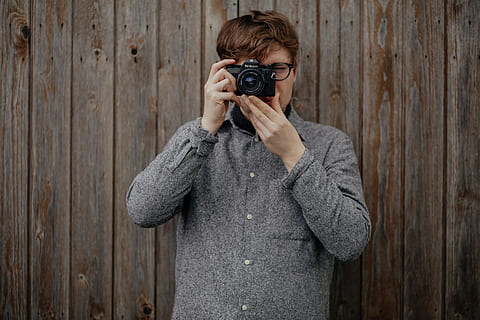 Mann, halten, schwarz, Brückenkamera, nehmen, Foto, Stehen, braun, hölzern, Wand, grau, Manteljacke, Mann in Grau, Mantel, Jacke, DSLR-Kamera, Kamera - Fotoausrüstung, Erwachsene, eine Person, Fotograf, kaukasischer Abstammung, nur für Erwachsene, Menschen, altmodisch, Fotografieren, Fotografie-Themen, Retro-Stil, lächelnd, kopieren sie platz, junger Erwachsener, suchen, Kamera betrachten, Männer, Farbbild, Porträt, Legere Kleidung, draußen, Hobbys, Nur ein Mann, Aktivität, Technologie, Taille hoch, Lebensstile, Freizeitbeschäftigung, Holz - Material, Vorderansicht, Besetzung, verdecktes Gesicht, Digitalkamera, 5K
