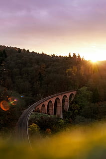 daurat, fotografia horària, ferrocarril, gris, concret, pont, verd, fulles, arbres, durant el dia, bosc, posta de sol, sol, arbre, cel, planta, estructura construïda, connexió, pont - estructura feta per l'home, naturalesa, transport, arc, arquitectura, pont d’arc, cap gent, llum solar, bellesa a la natura, flare de la lent, a l'aire lliure, transport per ferrocarril, 5K, CC0, domini públic, lliure de regalies