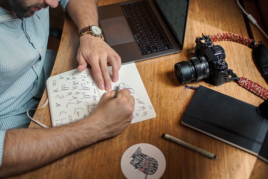 uomo, scrittura, carta, il computer portatile, computer, telecamera, elettronico, tecnologia, ufficio, lavoro, scrivania, attività commerciale, penna, taccuino, persone, Scrivi, disegno, uomini, in casa, mano umana, una persona, parte del corpo umano, tavolo, mano, creatività, adulto, legno - materiale, vista dall'alto, occupazione, macchina fotografica - attrezzatura fotografica, mobilia, Sezione centrale, arte e artigianato, 4K