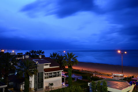 vista nocturna, platja, blau, mar, nit, posta de sol, vespre, exterior de l'edifici, arquitectura, estructura construïda, cel, aigua, il·luminat, clima tropical, núvol - cel, edifici, Palmera, arbre, ciutat, barri residencial, equips d’il·luminació, cap gent, casa, horitzó sobre l’aigua, a l'aire lliure, luxe, porpra, 5K, CC0, domini públic, lliure de regalies