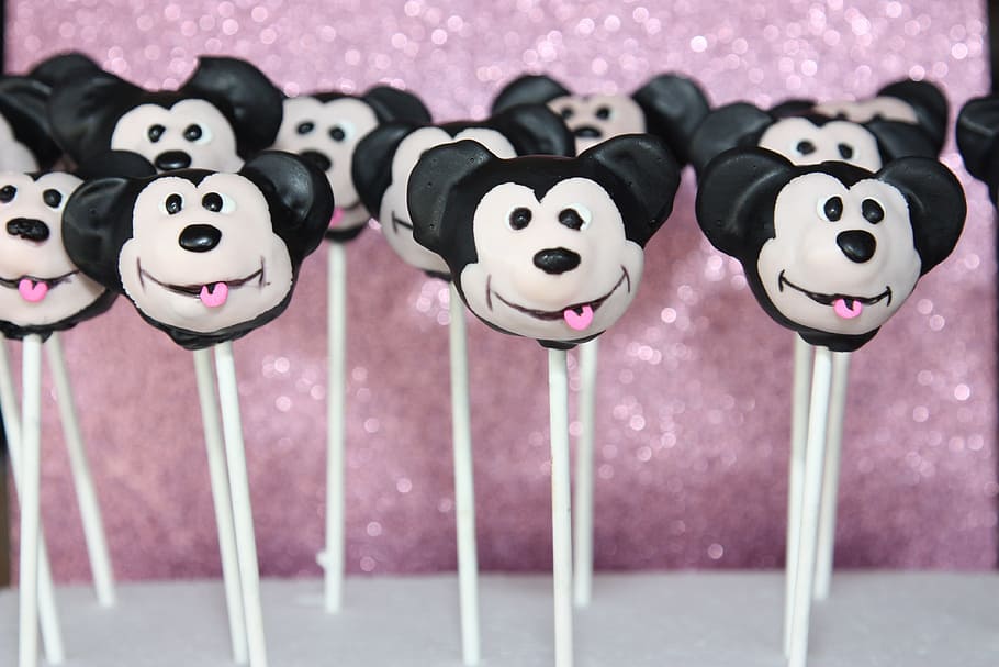 apareix el pastís, Mickey Mouse, dolços, postres, pals, llaminadures, cara, diversió, celebració, menjar, comestible, decorat, gel, representació, cap gent, representació animal, a l'interior, color rosa, primer pla, art i artesania, mamífer, natura morta, creativitat, joguina, animal, frescor, grup d'objectes, centrar-se en primer pla, menjar i beguda, elecció, variació, menjar poc saludable, 4K