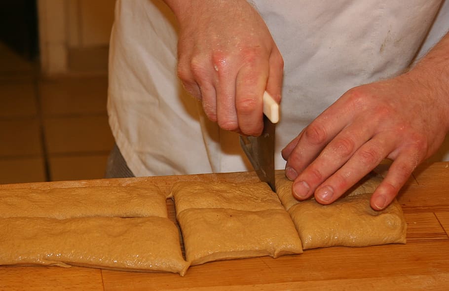 pa, italià, menjar, ciabattastykker, artesania, peça, forner, cocció, bonic, pa d'esmorzar, especialitat, massa, cuinar, producció, talla, mà humana, homes, ganivet de cuina, xef, cuina domèstica, tall, preparació, gent, treball, a l'interior, menjar i beguda, taula de tallar, material de fusta, eina de treball, artesà, activitat de talla - artesania, habilitat, part del cos humà, una persona, mà, ocupació, persones reals, secció mitjana, celebració, art i artesania, taula, preparar el menjar, primer pla, 2K