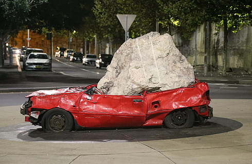 red, car, squashed, gray, stone, crushed, art, modern, sculpture, mode of transportation, transportation, motor vehicle, land vehicle, street, city, tree, day, road, plant, no people, architecture, travel, outdoors, focus on foreground, nature, close-up, 5K, CC0, public domain, royalty free