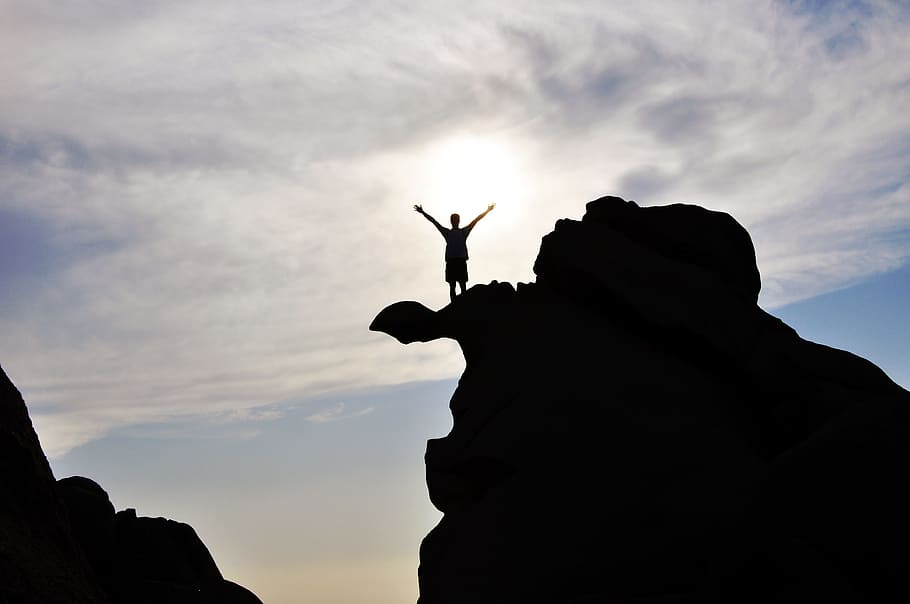 light, sky, man, person, backlit, clouds, outdoors, silhouette, cloud - sky, rock, solid, rock - object, lifestyles, leisure activity, one person, low angle view, nature, real people, men, human arm, rock formation, sunset, standing, arms raised, 4K