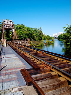 railroad tracks, perspective, train tracks, path, water, sky, clear sky, tree, plant, nature, day, no people, architecture, built structure, copy space, river, transportation, blue, wood - material, rail transportation, outdoors, track, 2K, CC0, public domain, royalty free