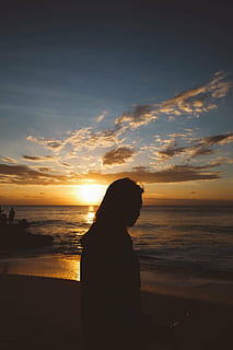 silhouette, person, front, beach, sunset, near, body, water, blue, cloudy, sky, clouds, shore, coast, sea, ocean, sand, people, woman, horizon over water, cloud - sky, one person, tranquil scene, spirituality, land, beauty in nature, scenics - nature, horizon, real people, lifestyles, leisure activity, tranquility, orange color, outdoors, looking at view, 4K