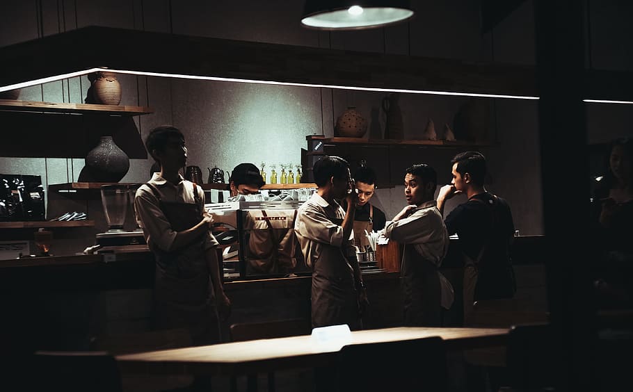 folk inde restaurant, mand, iført, Brun, forklæde, restaurant, cafe, personale, samtale, køkken, madlavning, mandskab, mennesker, indendørs, herrer, ung voksen, kun voksne, stående, voksen, unge mænd, gruppe af mennesker, gruppe, rigtige mennesker, Kvinder, menneskemængde, stor gruppe mennesker, belyst, belysningsudstyr, livsstil, uniform, kommercielt køkken, beskæftigelse, tøj, bagfra, 4K
