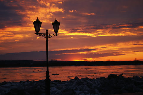 posta de sol, llanterna, riu, sol, cel, núvol - cel, color taronja, bellesa a la natura, equips d’il·luminació, aigua, escenics - natura, llum del carrer, naturalesa, cap gent, silueta, tranquil·litat, carrer, mar, escena tranquil·la, a l'aire lliure, platja, idíl·lic, 4K, CC0, domini públic, lliure de regalies