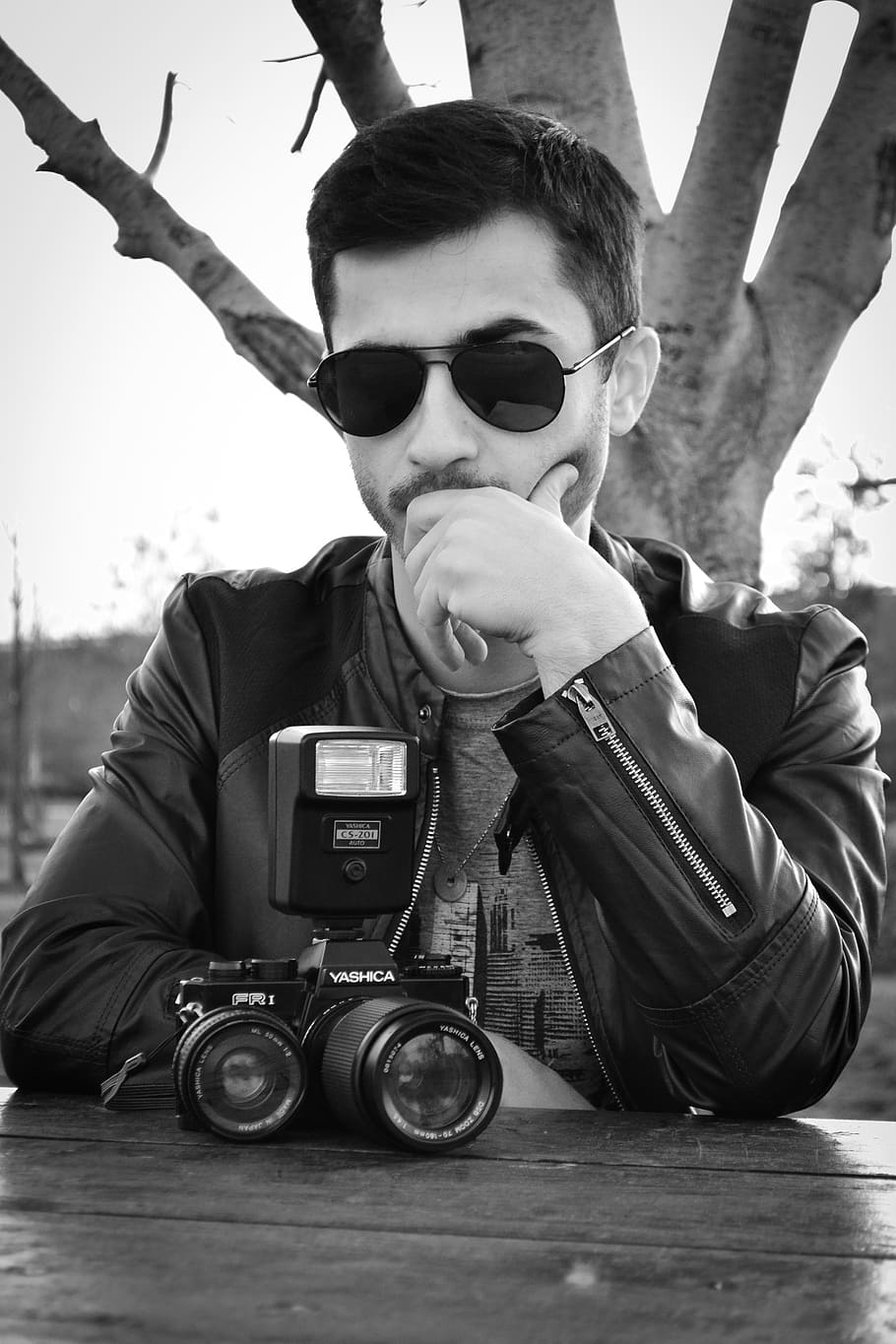 ung mand, gammelt kamera, briller, alvorlig, tænker, Foto, dreng, kamera - fotografisk udstyr, sort og hvid, herrer, mennesker, en person, fotograf, udendørs, hanner, kaukasisk etnicitet, retro stylet, gammeldags, rigtige mennesker, solbriller, portræt, sidder, forfra, mode, livsstil, fritidsaktivitet, unge mænd, ung voksen, afslappet tøj, hovedskud, meddelelse, teknologi, dag, 2K