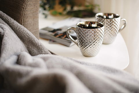 dos, tasses de plata, blanc, tauleta auxiliar, tasses de color blanc i plata, taula, tasses, parell, sofà, manta, a l'interior, enfocament selectiu, primer pla, tèxtil, tassa, menjar i beguda, cap gent, habitació domèstica, beure, mobles, la vida domèstica, equipament per a la llar, interior de casa, estri de cuina, metall, color plata, natura morta, casa, roba, luxe, 5K, CC0, domini públic, lliure de regalies