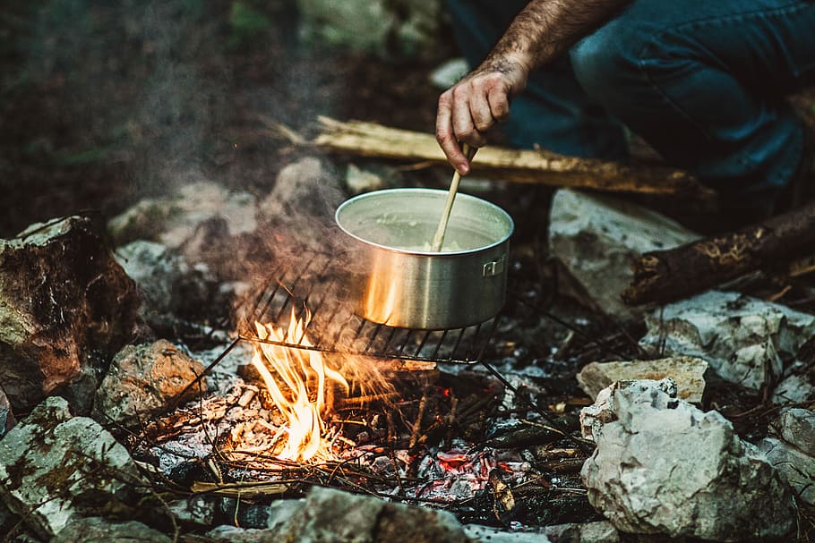 cuina persona, bonefire, persona, celebració, pal, cuinar, gris, inoxidable, olla d'acer, pan, olla, foguera, foc, flames, calor - temperatura, cremant, foc - fenomen natural, menjar i beguda, mà humana, estri de cuina, naturalesa, flama, preparació, menjar, persones reals, material de fusta, campament, una persona, mà, bosc, a l'aire lliure, fusta, 5K