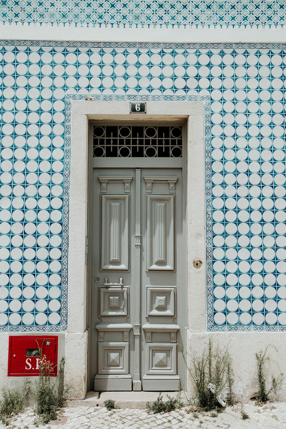 porta de fusta grisa, blanc, concret, edifici, durant el dia, porta, passatge, marc, cercle, entrada, estructura construïda, arquitectura, exterior de l'edifici, tancat, seguretat, dia, casa, protecció, cap gent, funció de construcció de parets, a l'aire lliure, finestra, material de fusta, barri residencial, blau, porta principal, 5K