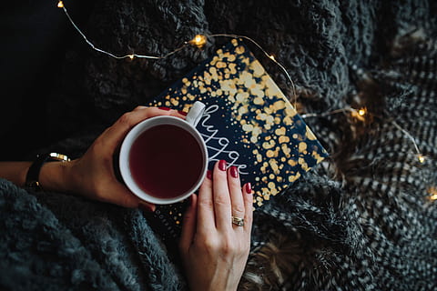 young, woman, home reading hygge book, drinking, at home, reading, Hygge, book, home, indoor, femine, cosy, cozy, fairy lights, coffee - Drink, cup, one Person, women, people, drink, heat - Temperature, relaxation, coffee Cup, adult, close-up, lifestyles, one woman only, only women, human body part, adults only, human hand, hand, holding, mug, food and drink, real people, coffee, leisure activity, warm clothing, high angle view, nail, finger, 5K