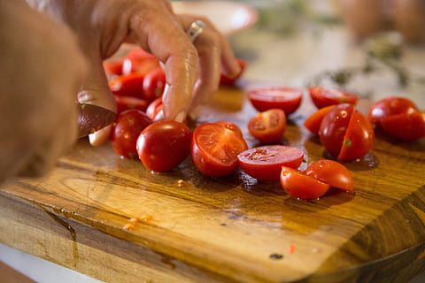 tomàquets en persona a rodanxes, tallar, cuina, cuinar, tall, menjar, taula de tallar, tomàquet, preparar-se, verdures fresques, vegetals, orgànic, pissarra, ganivet, taula, fusta, fresc, menjar i beguda, fruita, alimentació saludable, frescor, material de fusta, una persona, benestar, enfocament selectiu, part del cos humà, primer pla, mà, estils de vida, mà humana, preparar el menjar, vida senzilla, madur, berenar, 5K, CC0, domini públic, lliure de regalies