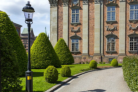 architecture, building, castle, clouds, facade, garden, hedge, lamp post, landmark, lawn, mansion, outdoors, plants, shadow, sky, street lamp, windows, built structure, building exterior, plant, nature, tree, city, day, green color, no people, topiary, formal garden, street, the past, growth, history, street light, ornamental garden, 5K, CC0, public domain, royalty free