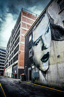 painting, woman, concrete, wall, cloudy, sky, photo, beige, printed, building, architecture, infrastructure, cloud, road, street, face, female, building exterior, city, outdoors, city life, cloud - sky, day, modern, one young woman only, built structure, no people, art and craft, low angle view, nature, transportation, creativity, human representation, representation, office building exterior, digital composite, mural, 5K