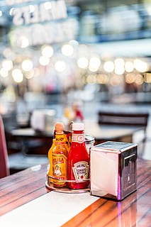 heinz paradicsom ketchup palack, sekély, fókusz fotózás, szürke, rozsdamentes, acél szövetadagoló, mellett, asztal, tartály, üveg, üveg - anyag, összpontosít az előtérre, nem ember, átlátszó, csendélet, fedett, megvilágított, közelkép, étterem, napfény, nap, természet, üzleti, piros, étel és ital, fa - anyag, 5K, CC0, közkincs, jogdíjmentes