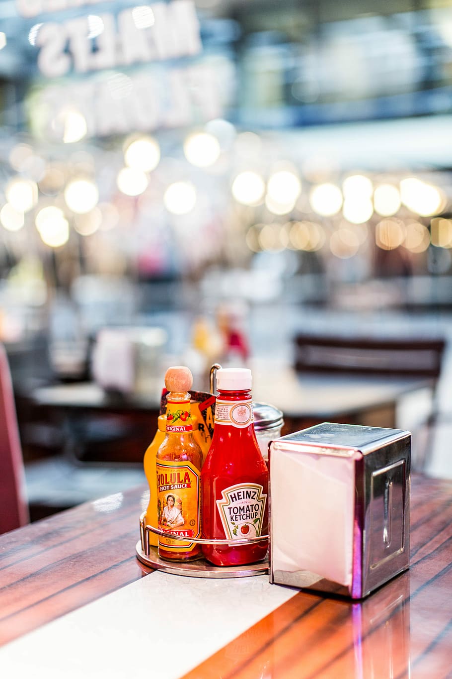 bottiglia di ketchup di pomodoro Heinz, superficiale, fotografia a fuoco, grigio, inossidabile, distributore di tessuti in acciaio, accanto, tavolo, contenitore, bottiglia, vetro - materiale, concentrarsi sulle conoscenze acquisite, nessuno, trasparente, natura morta, in casa, illuminato, avvicinamento, ristorante, luce del sole, giorno, natura, attività commerciale, rosso, cibo e bevande, legno - materiale, 5K