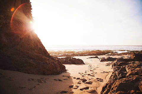 beach, footprints, rocks, sand, sunshine, sea, nature, sunset, outdoors, coastline, rock - Object, land, water, sky, rock, solid, tranquility, beauty in nature, scenics - nature, sunlight, tranquil scene, horizon over water, no people, horizon, lens flare, 4K, CC0, public domain, royalty free