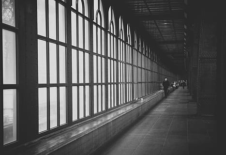 grayscale photo, man, walking, hallway, glass window, grayscale, photo, building, architecture, windows, black and white, indoors, real people, men, built structure, one person, day, full length, prison, direction, the way forward, transportation, window, incidental people, diminishing perspective, arcade, railing, lifestyles, corridor, ceiling, 5K, CC0, public domain, royalty free