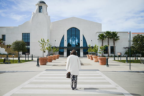 woman, walking, pedestrian, white, jacket, grey, top, road, daytime, Santa Barbara, airport, crosswalk, street, coat, purse, sidewalk, plants, pots, palm trees, architecture, sunny, rear view, building exterior, built structure, full length, cloud - sky, day, one person, outdoors, real people, building, lifestyles, sky, religion, adult, leisure activity, city, women, belief, nature, 1080P
