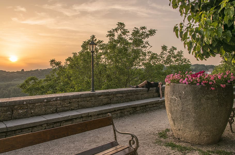 persona, estirat, banc, fanal, gris, cel, dona, posada, concret, tanca, posta de sol, arbre, jardinera de pedra, Banc del parc, paret, descans, parc, a l'aire lliure, horitzó, vista, model, dorment, planta, naturalesa, creixement, transport, núvol - cel, arquitectura, bellesa a la natura, dia, estructura construïda, llum solar, una persona, barana, persones incidentals, connexió, color verd, 5K