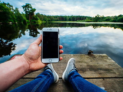 person, sidder, flod dock, bedrift, iphone, træer, cumulus skyer, æble, dok, hånd, sø, touchscreen, vand, trådløs teknologi, meddelelse, menneskelig kropsdel, menneskelig hånd, smart telefon, flod, bærbar informationsenhed, teknologi, mobiltelefon, fritidsaktivitet, en person, forbindelse, natur, livsstil, personlige perspektiv, dag, udendørs, kropsdel, jeans, 4K, CC0, offentligt domæne, royaltyfrie