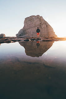 mand, stående, klippe, rock formation, afspejling, landskab, solnedgang, vand, shorts, kort, hajfin cove, himmel, skønhed i naturen, natur, ro, scenics - natur, havnefronten, rolig scene, dag, en person, bagfra, rigtige mennesker, sø, livsstil, symmetri, herrer, udendørs, 2K, CC0, offentligt domæne, royaltyfrie