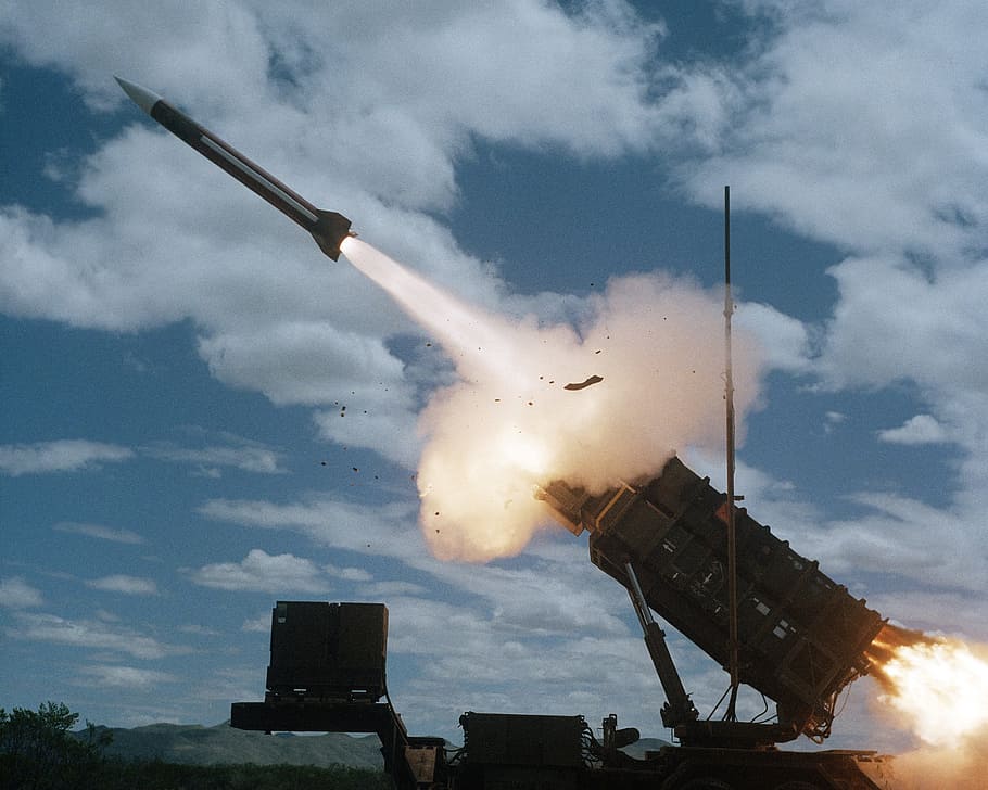 aereo, fotografia, razzo, lancio, giorno, fotografia aerea, arma, combattimento, violento, guerra, difesa, militare, Stati Uniti d'America, esercito, nuvola - cielo, tecnologia, all'aperto, conflitto, Inquadratura dal basso, cielo, architettura, natura, struttura costruita, esterno dell'edificio, fumo - struttura fisica, che esplode, nessuno, volante, veicolo aereo, movimento, illuminato, fuochi d'artificio - Oggetto creato dall'uomo, luce del sole, sicurezza, fuoco d'artificio, esplosivo, 2K