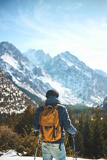 uomo, in piedi, detenzione, la neve, bastone, di fronte, montagna, indossare, blu, giacca a bolle, bastoncini da sci, foresta, escursione, zaino, arancia, giacca, luce del sole, polo, escursioni a piedi, albero, pino, verde, all'aperto, escursionista, cielo, tipo, esploratore, esplorando, una persona, persone reali, attività di svago, bellezza nella natura, catena montuosa, retrovisore, avventura, inverno, stili di vita, scenics - natura, natura, capi di abbigliamento, giorno, attività, scena non urbana, vestiti caldi, guardando a vista, 5K, CC0, dominio pubblico, privo di copyright