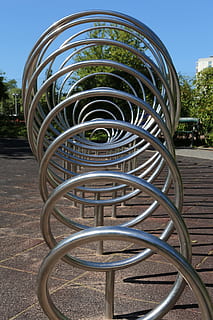 parc infantil, cadenes, crom, espiral, cercle, metall, dia, cap gent, naturalesa, suport per a bicicletes, a l'aire lliure, centrar-se en primer pla, parc, parc - l'home va fer espai, ciutat, arquitectura, patró, llum solar, buit, planta, forma, absència, cel, bicicleta, 5K, CC0, domini públic, lliure de regalies