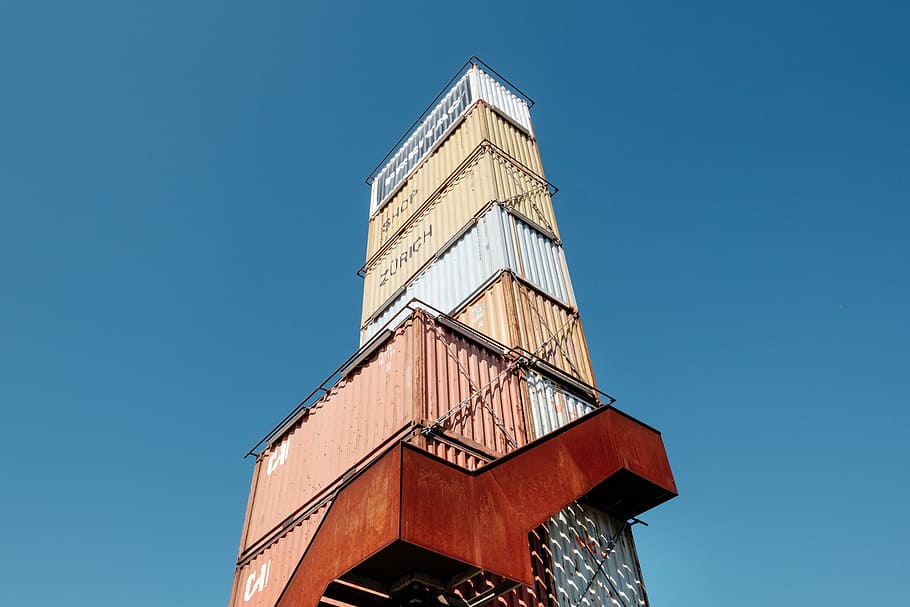 Versandbehälter aus Metall, Intermodaler Container in verschiedenen Farben, Gebäude, Ladung, Kiste, Container, gewellt, Haufen, Stapel, Blau, Himmel, treppe, intermodaler Container, Fracht, blauer Himmel, städtisch, Stadt, klarer Himmel, Flachwinkelansicht, die Architektur, gebaute Struktur, Turm, Gebäudehülle, Natur, keine Leute, Sonnenlicht, Tag, sonnig, draußen, große Höhe, Reiseziele, Reise, kopieren sie platz, 4K