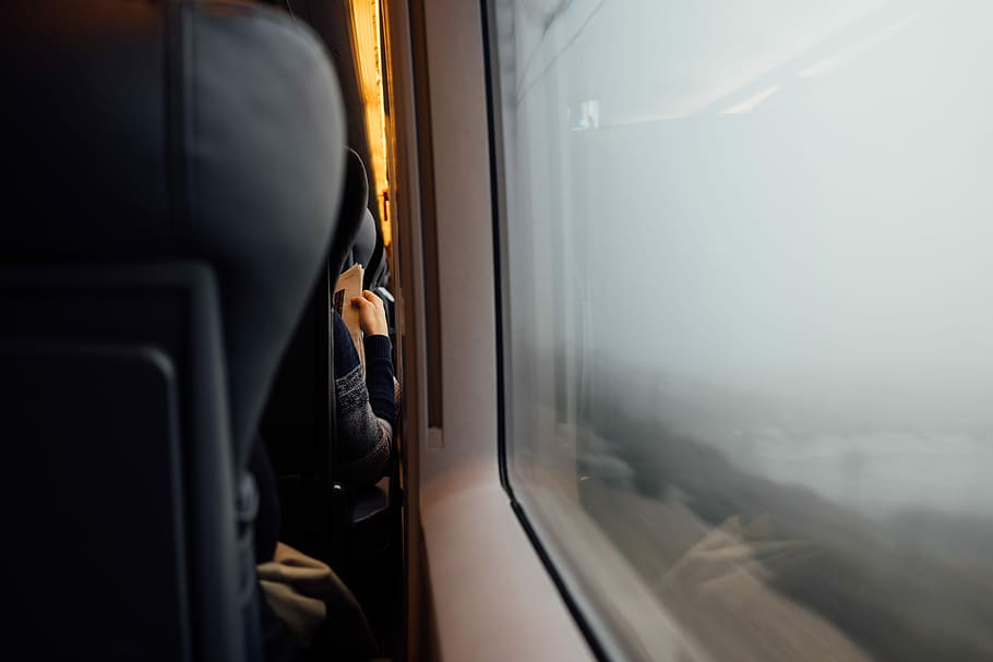 persona che legge il giornale, dietro a, poggiatesta, primo piano, finestra del vagone ferroviario, sedia da autobus nera, finestra, treno, persona, lettura, giornale, posto a sedere, posti a sedere, carrozza ferroviaria, tipo, uomo, mano, seduta, piovere, nebbioso, modo di trasporto, mezzi di trasporto, interno del veicolo, viaggio, trasporto pubblico, una persona, trasporto ferroviario, treno - veicolo, adulto, treno passeggeri, sedile del veicolo, aereo, detenzione, in movimento, all'aperto, 5K