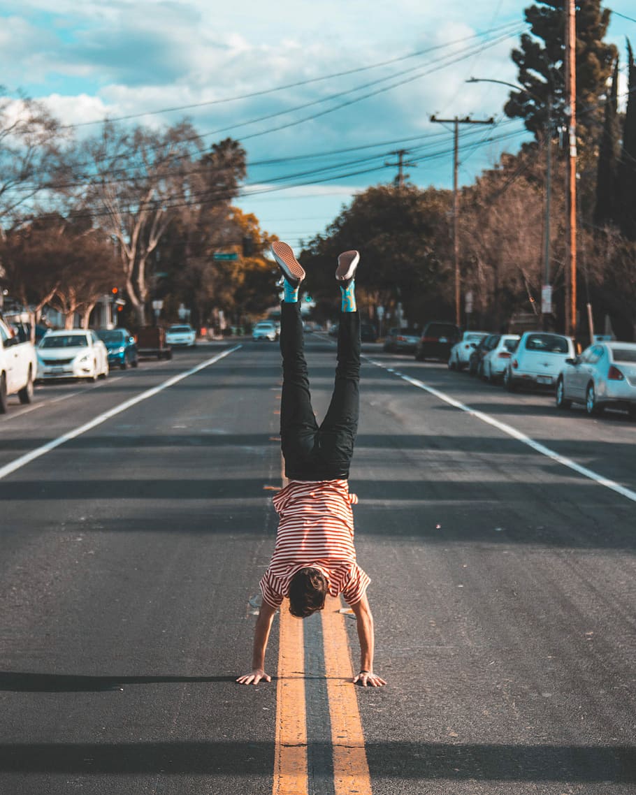 homem, mãos, ficar de pé, estrada de asfalto, arvores, mão, Centro, estrada, parada de mãos, de cabeça para baixo, caminhando, transporte, cidade, carro, estilos de vida, veículo motorizado, uma pessoa, modo de transporte, rua, atividade de lazer, comprimento total, pessoas reais, visão traseira, céu, veículo terrestre, dia, equilibrar, natureza, placa, marcação de estrada, braço humano, ao ar livre, braços levantados, 2K
